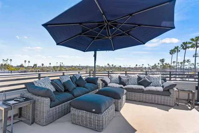 a view of a roof deck with couches under an umbrella