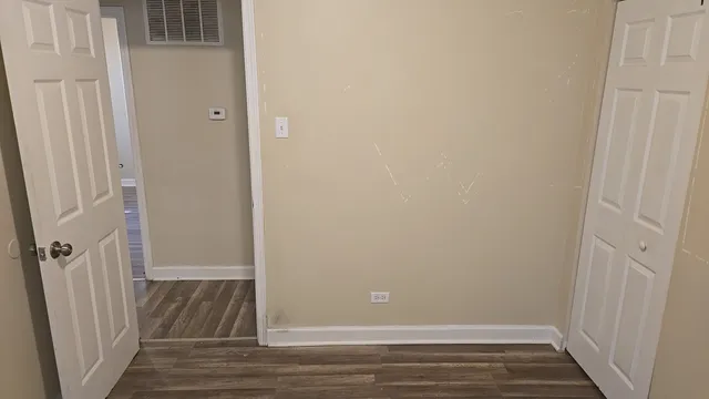 an empty room with wooden floor and entrance