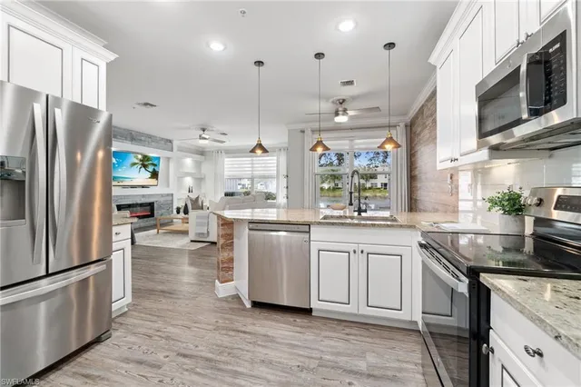 a kitchen with stainless steel appliances granite countertop a refrigerator a stove a sink and white cabinets