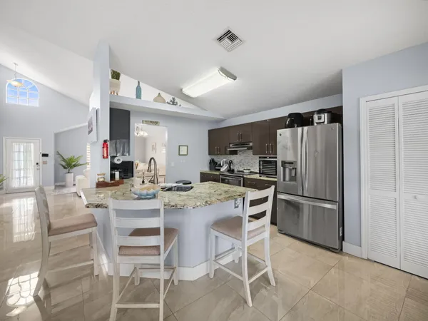 a kitchen with stainless steel appliances kitchen island granite countertop a dining table and chairs