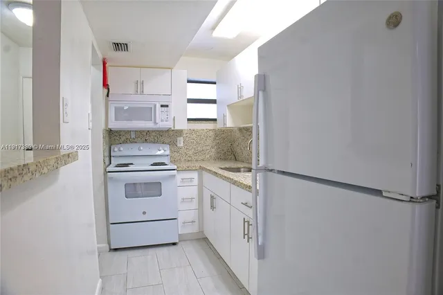a kitchen with white cabinets and white appliances