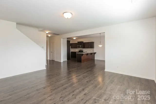 a view of a livingroom with wooden floor and staircase