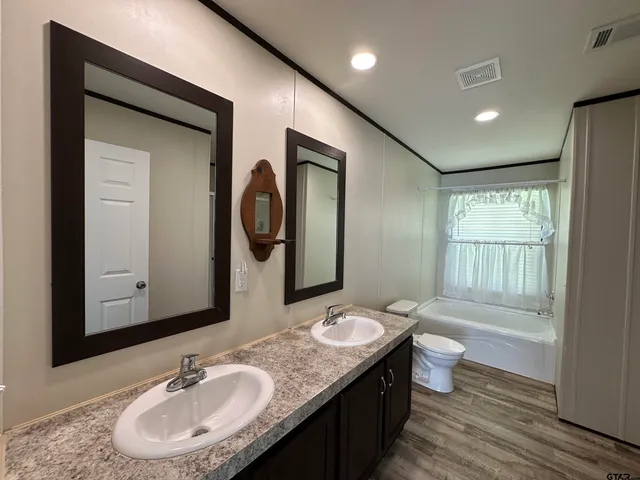 a bathroom with a granite countertop sink toilet and mirror