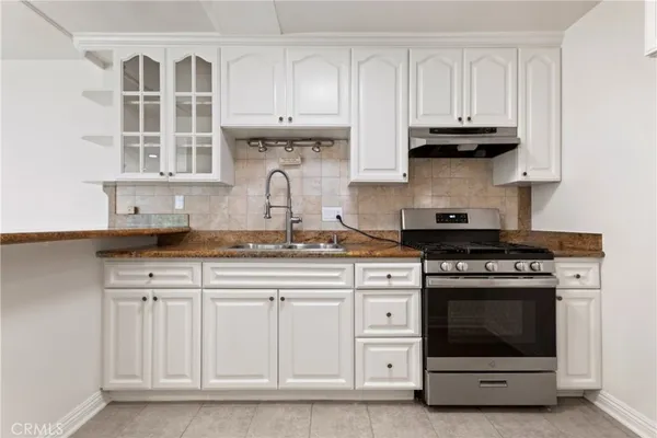 a kitchen with granite countertop white cabinets and stainless steel appliances