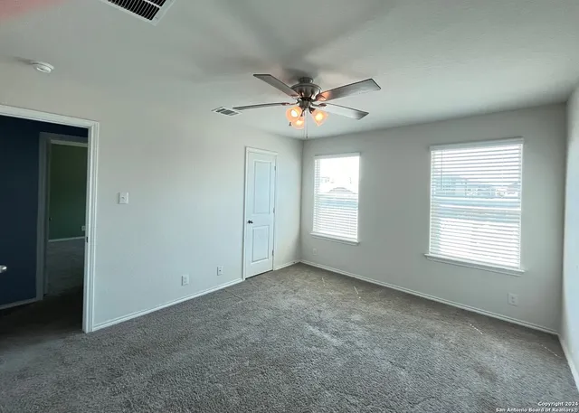 an empty room with windows and fan