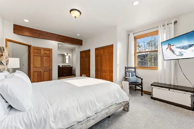 a spacious bedroom with a bed a dresser and a flat tv screen