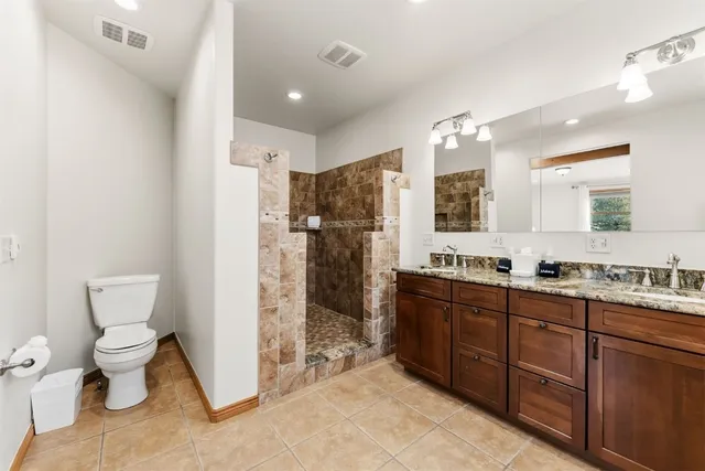 a bathroom with a granite countertop shower a sink and a toilet