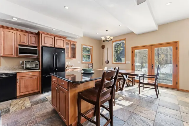 a kitchen with stainless steel appliances granite countertop a stove refrigerator a table and chairs