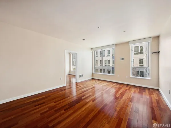 a view of an empty room with wooden floor and a window