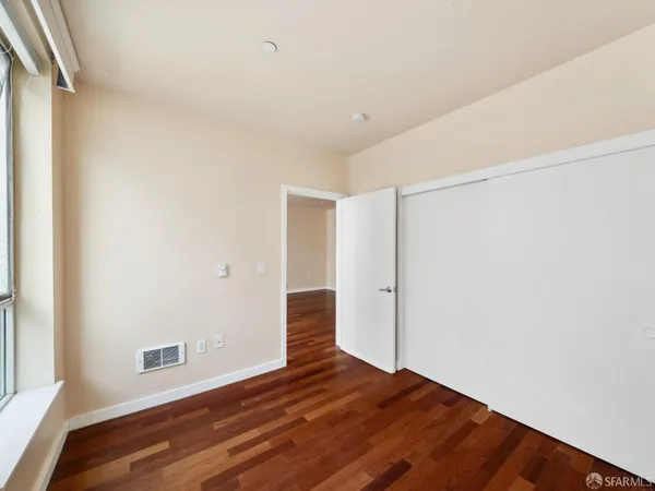 a view of an empty room with wooden floor and a window