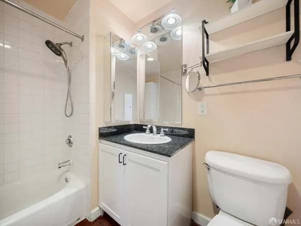 a bathroom with a granite countertop sink a toilet a mirror and shower