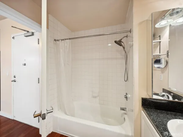 a bathroom with a granite countertop shower sink vanity and a mirror