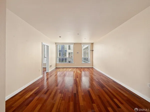 an empty room with wooden floor and windows