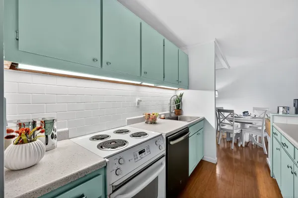 a kitchen with a stove and a wooden floor