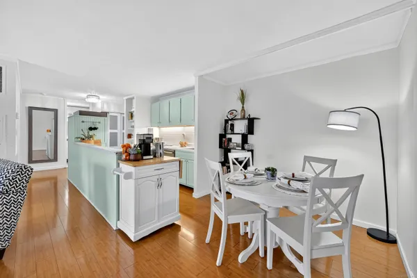 a kitchen with stainless steel appliances kitchen island a table chairs in it and wooden floors