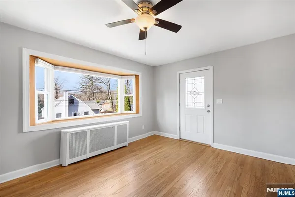 an empty room with wooden floor chandelier and windows