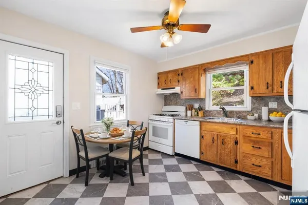 a kitchen with stainless steel appliances granite countertop a sink a stove a dining table and chairs with wooden floor