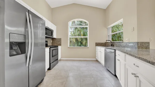 a view of a hallway to an empty room with wooden floor and a window