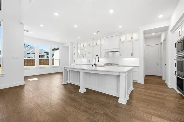 a kitchen with stainless steel appliances kitchen island hardwood floor sink and stove