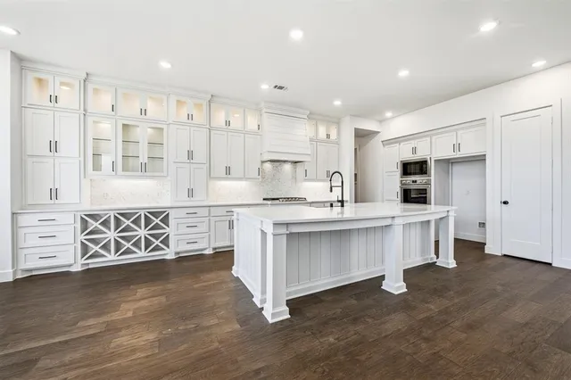 a large white kitchen with white cabinets and wooden floor