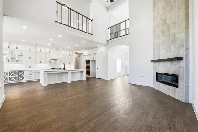 a view of an empty room and kitchen with fireplace wooden floor