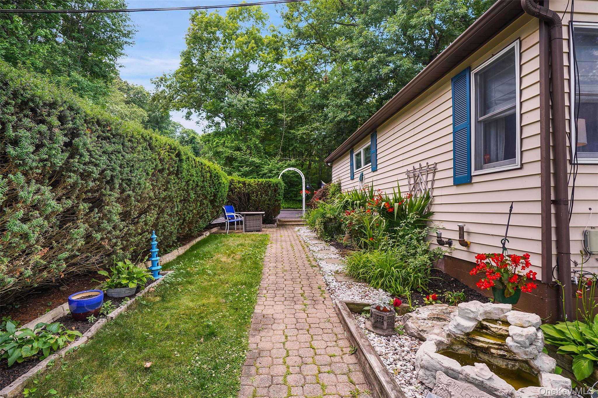 18 Sylvan Road Lake Peekskill, NY 10537 - Photo 41 of 50 Side yard featuring a paver walkway, extensive landscaping, and privacy hedging
