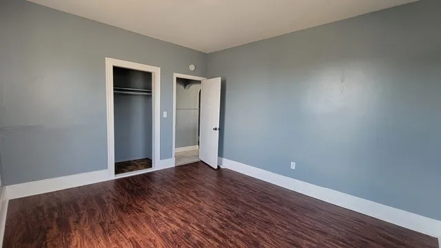 a view of an empty room with wooden floor and closet
