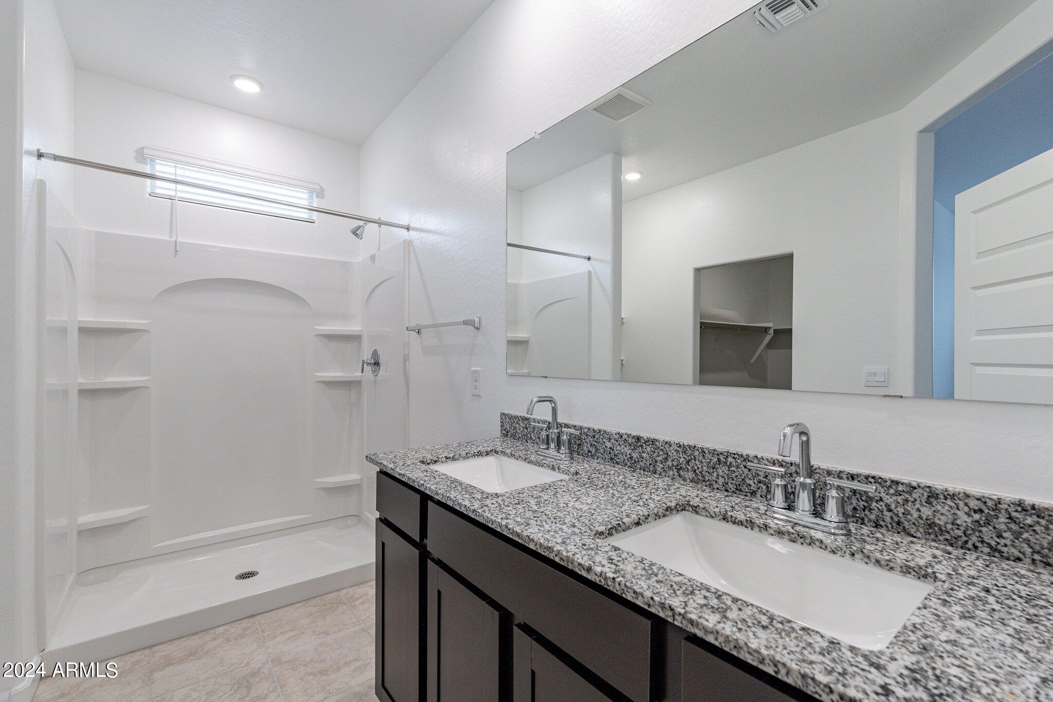 5447 Azara Drive San Tan Valley, AZ 85140 - Photo 12 of 21 a bathroom with a granite countertop sink a mirror and a shower