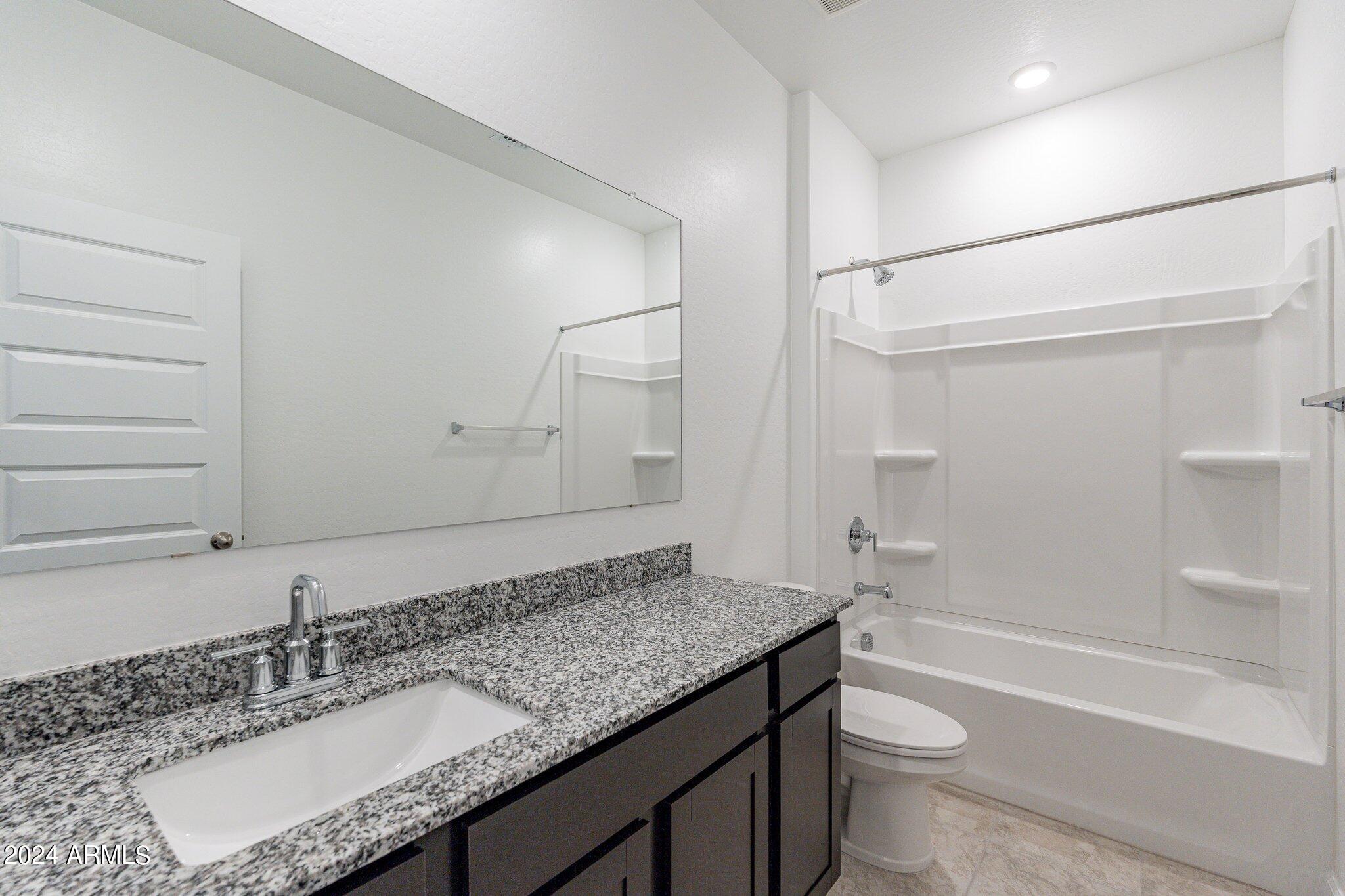 5447 Azara Drive San Tan Valley, AZ 85140 - Photo 18 of 21 a bathroom with a granite countertop sink a toilet and shower