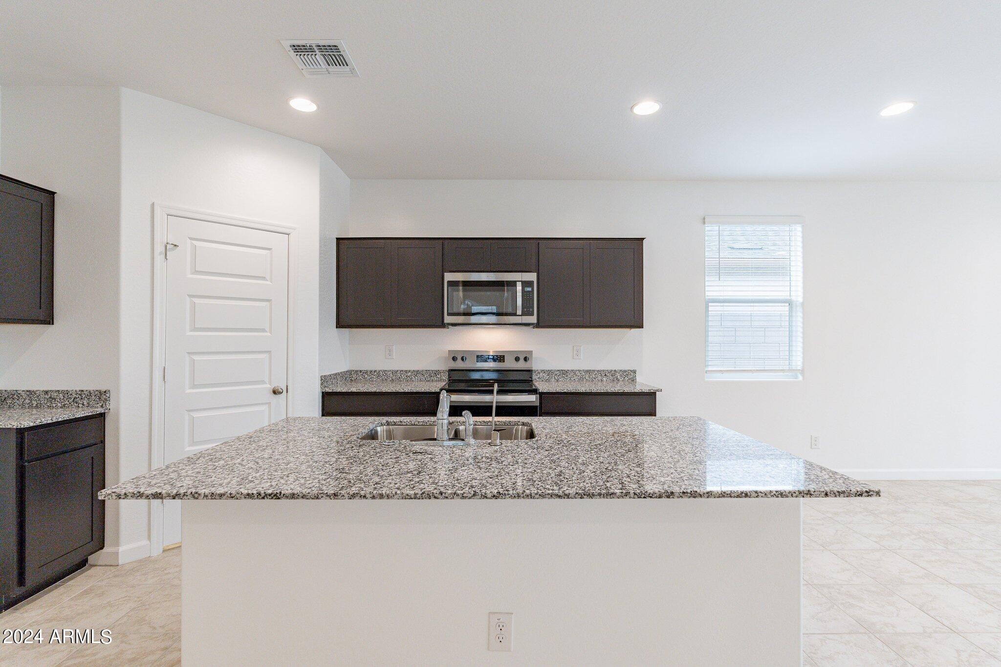 5447 Azara Drive San Tan Valley, AZ 85140 - Photo 5 of 21 a kitchen with granite countertop a sink and a stove top oven