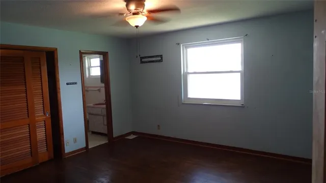 an empty room with wooden floor closet and windows