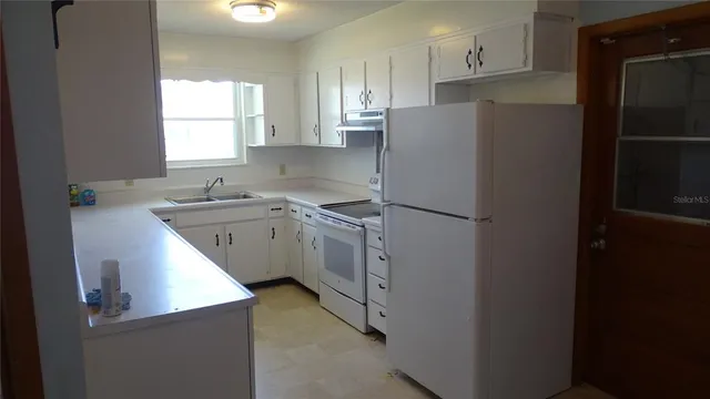 a kitchen with a refrigerator sink and cabinets