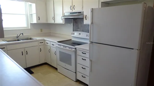 a kitchen with cabinets appliances and a window