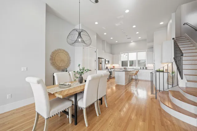 a dining room with wooden floor a chandelier a wooden table and chairs