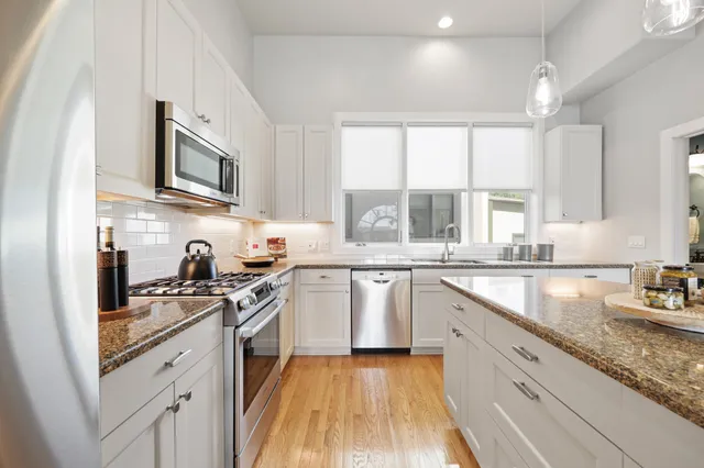 a kitchen with granite countertop cabinets stainless steel appliances a sink and a window