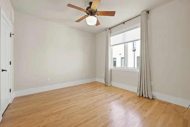 a view of an empty room with window and a ceiling fan
