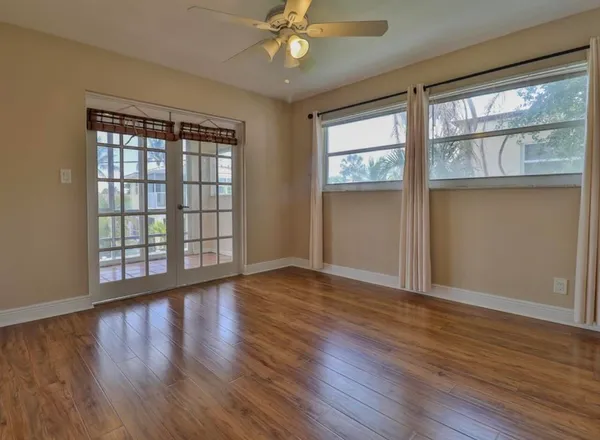 a view of an empty room with wooden floor and a window