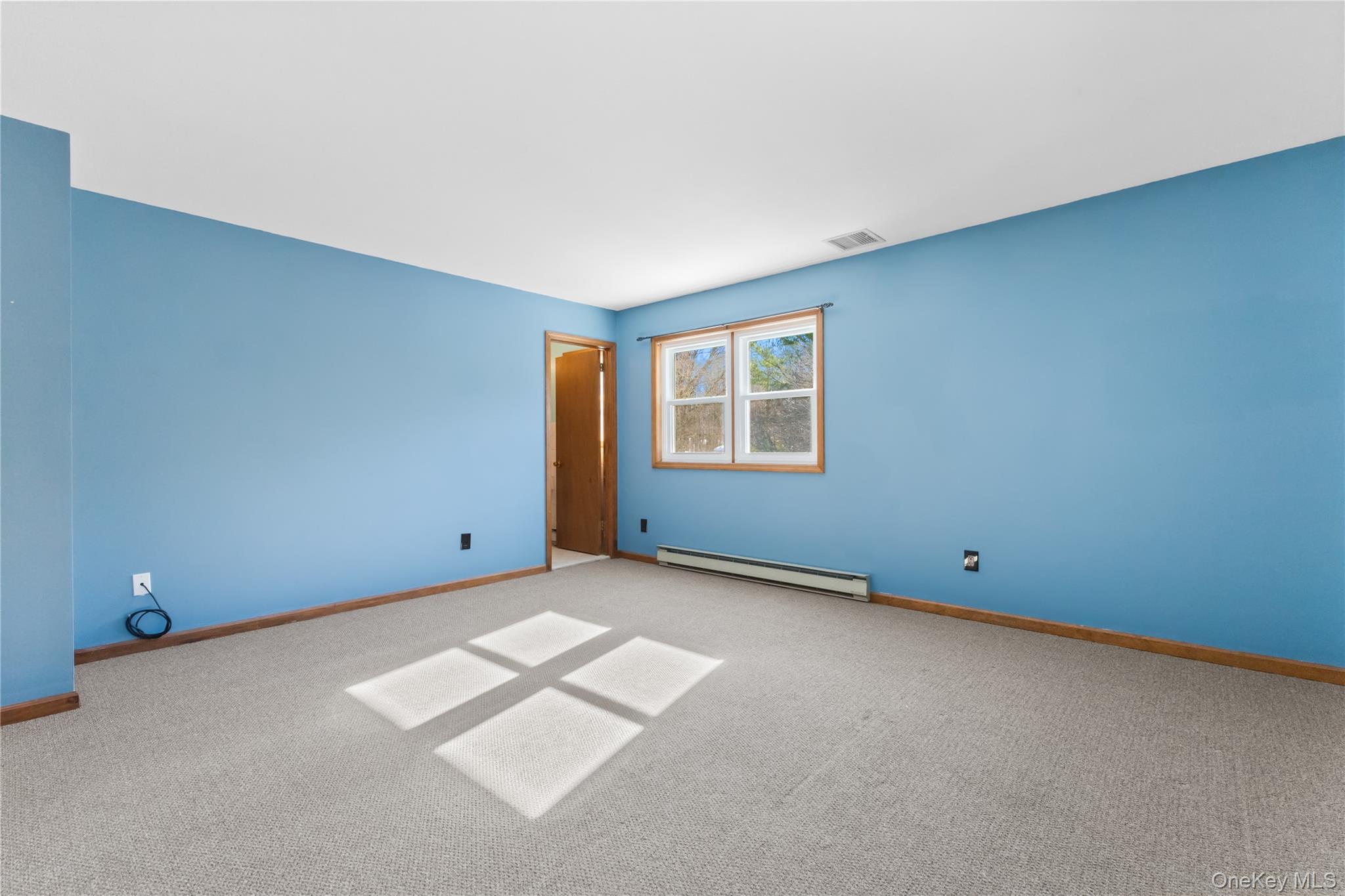 7 Cimarron Road Putnam Valley, NY 10579 - Photo 31 of 50 Spacious primary bedroom with calming blue walls, soft carpeting, and bright windows that fill the room with natural light.