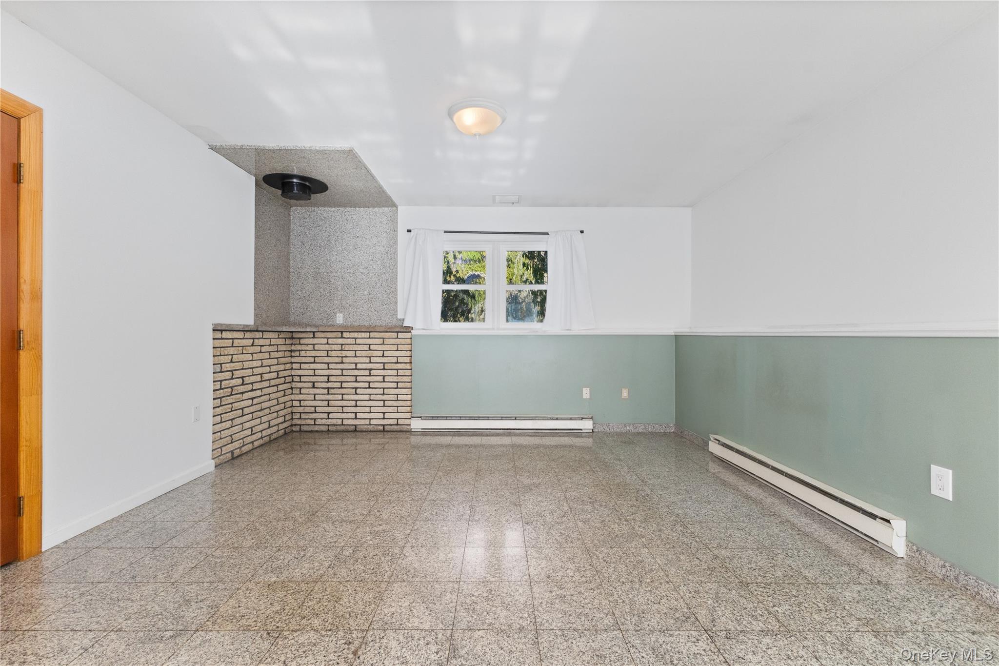 7 Cimarron Road Putnam Valley, NY 10579 - Photo 40 of 50 Versatile lower-level living space with tile flooring, a charming brick accent, and a bright window for natural light.