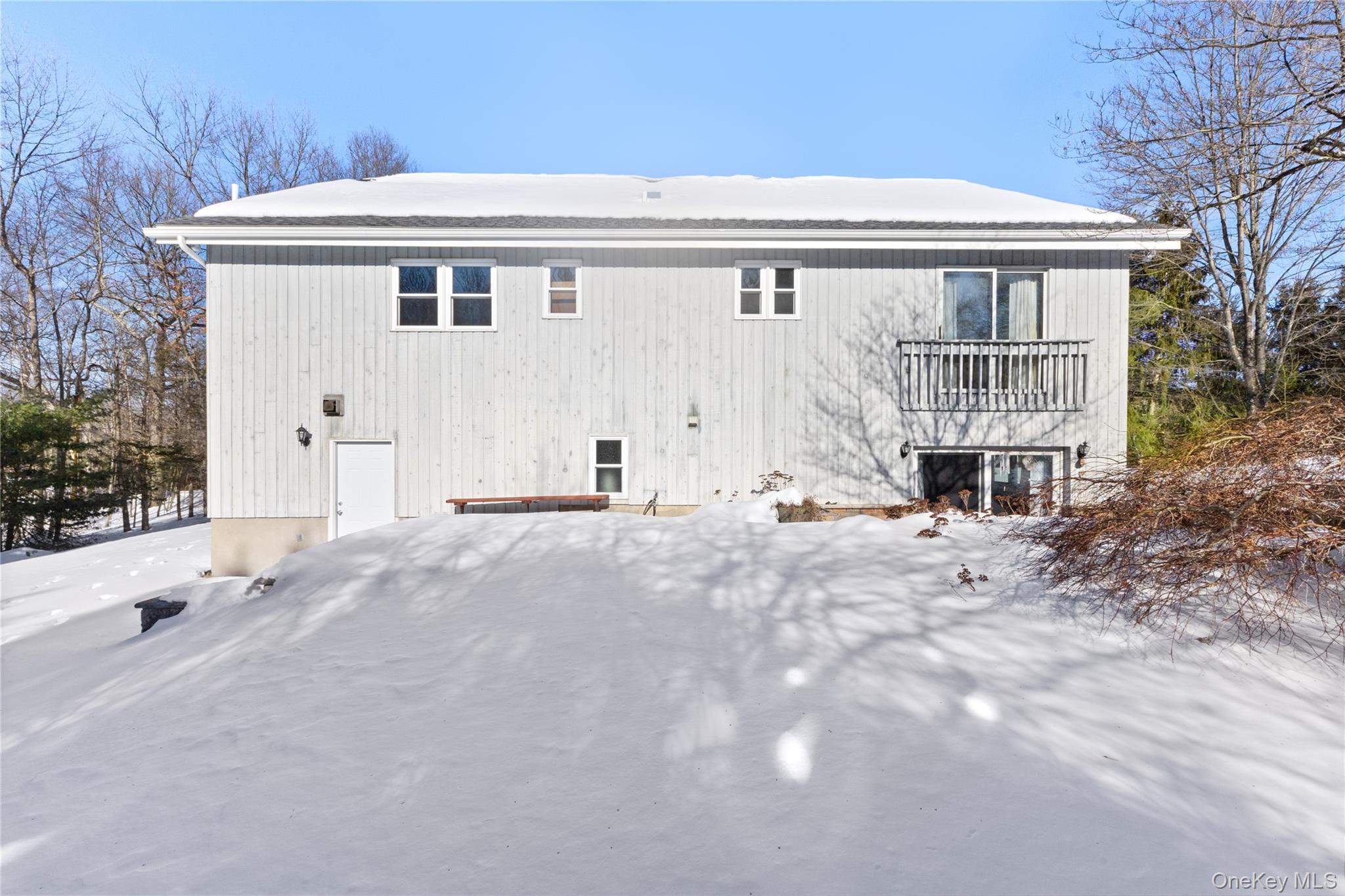7 Cimarron Road Putnam Valley, NY 10579 - Photo 45 of 50 Rear view of the home overlooking a spacious backyard—currently blanketed in snow but offering plenty of open space for outdoor enjoyment in warmer months.