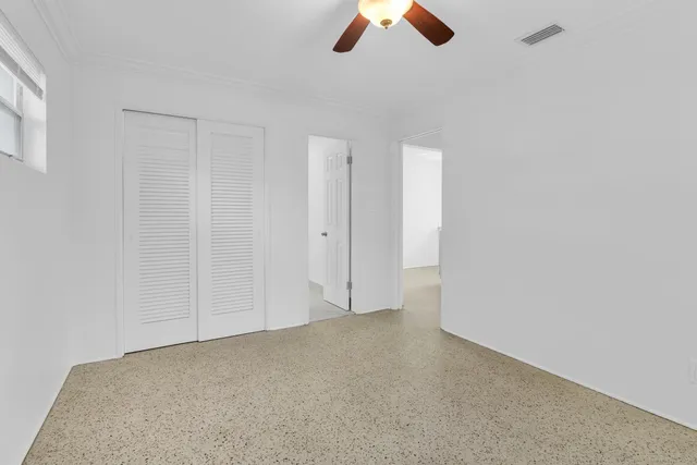 an empty room with ceiling fan and window