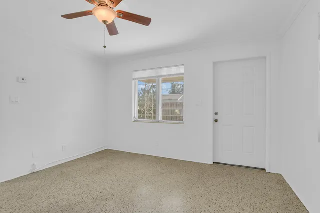 an empty room with a window and a fan