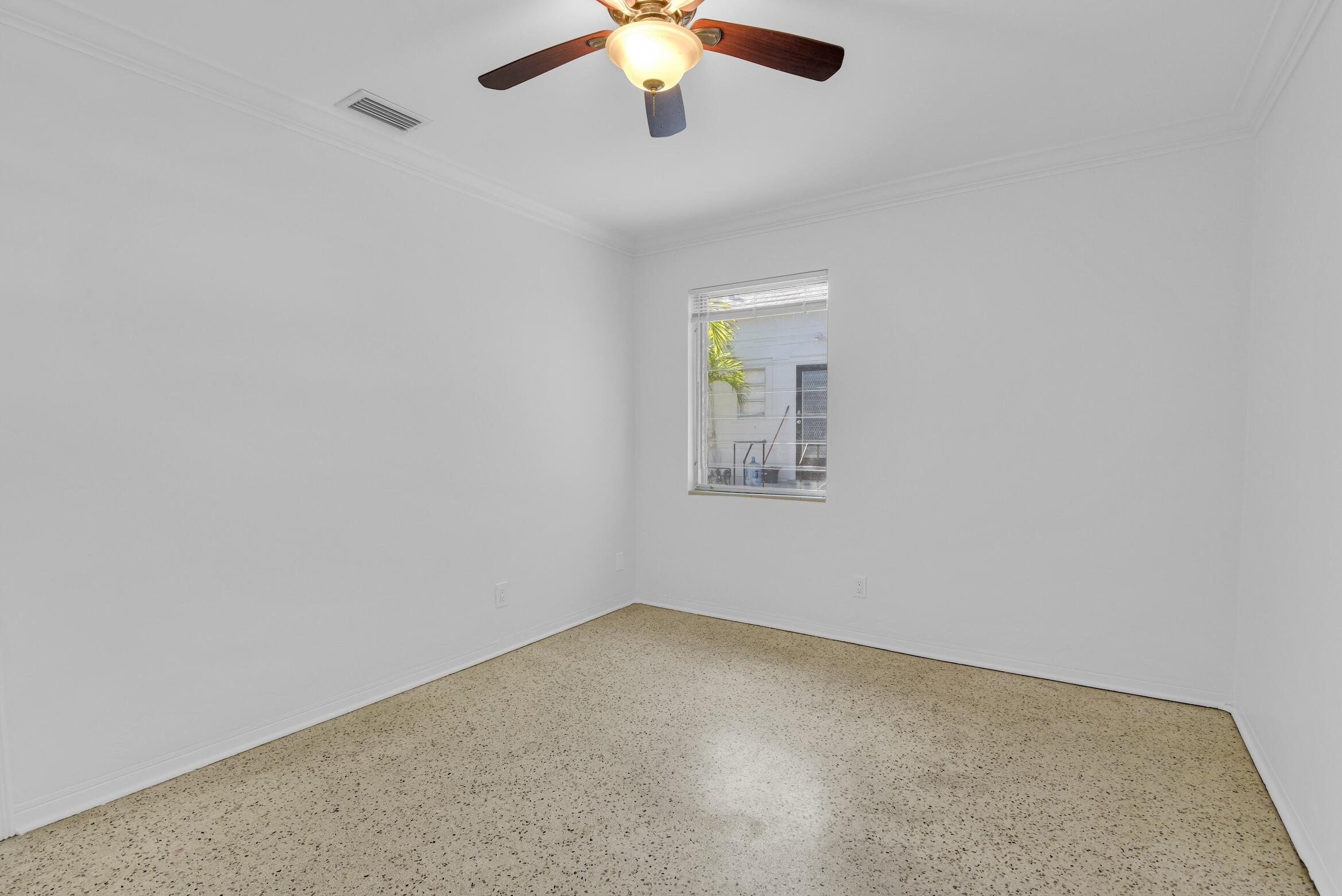 728 North L Street, Unit 2 Lake Worth Beach, FL 33460 - Photo 10 of 13 an empty room with a chandelier fan and windows