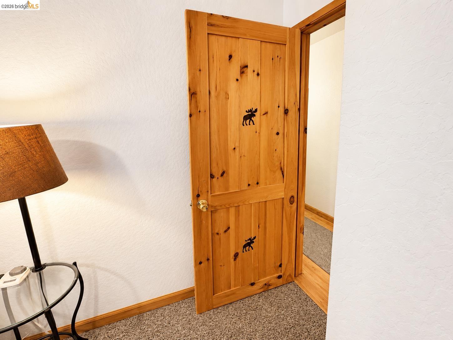 21181 Phoenix Lake Road Sonora, CA 95370 - Photo 30 of 34 Knotty pine door with decorative wildlife accents, brass-tone hardware, wood-finish door frame, and textured white wall finish