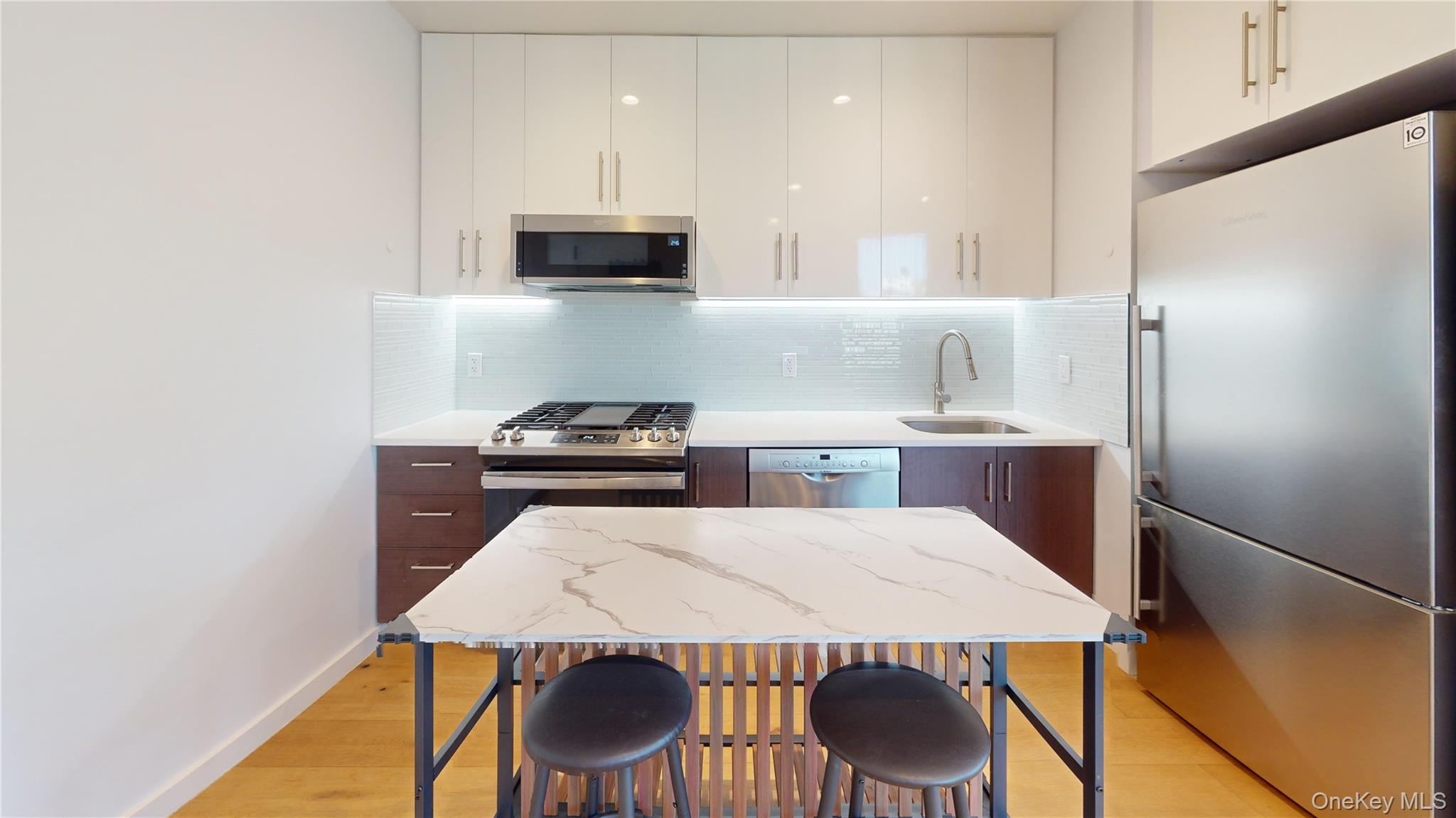 97-29 64th Road Queens, NY 11374 - Photo 2 of 11 a kitchen with stainless steel appliances kitchen island a table chairs and a refrigerator