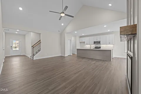 a kitchen with stainless steel appliances granite countertop a sink a stove a refrigerator and white cabinets with wooden floor