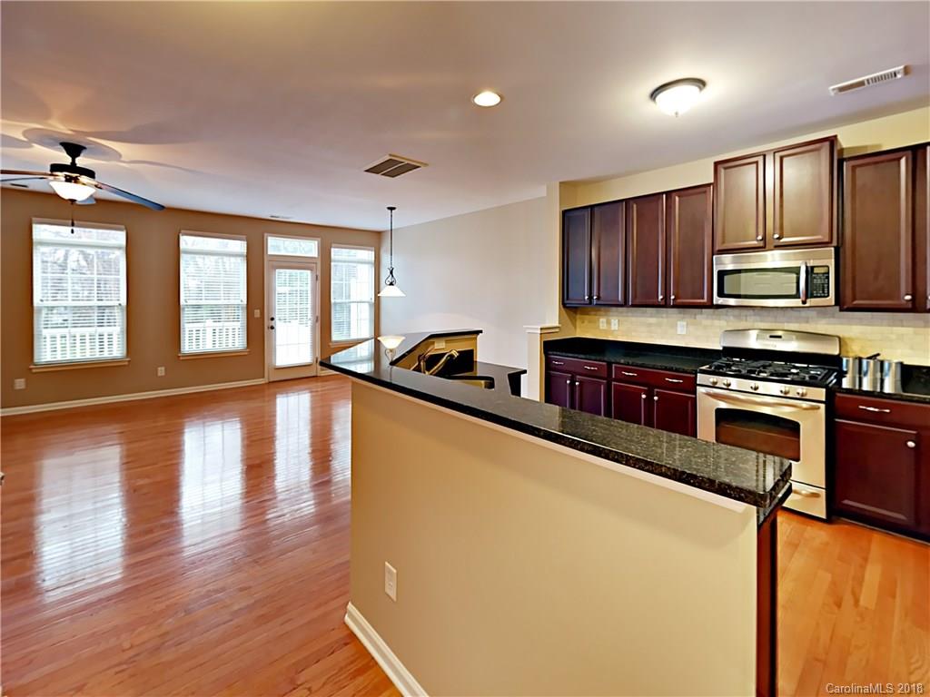 813 Kimbrough Court Davidson, NC 28036 - Photo 6 of 22 a large kitchen with stainless steel appliances granite countertop a stove a sink dishwasher a microwave oven and a dining table with wooden floor