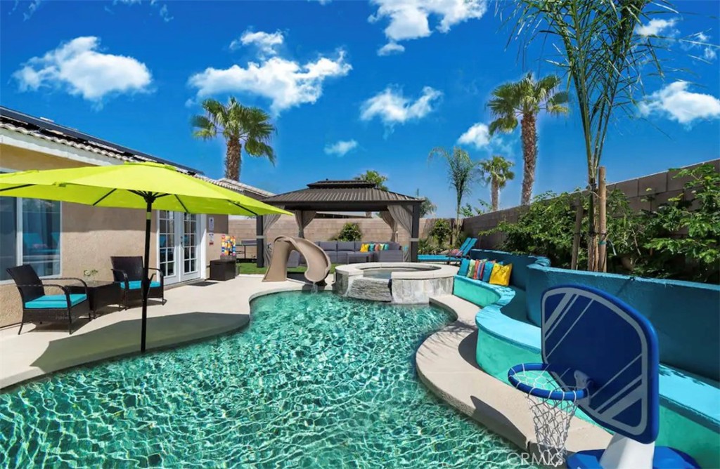 a view of a patio with couches table and chairs under an umbrella with a fire pit