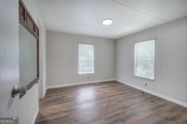 an empty room with wooden floor and windows