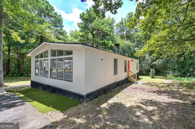 a view of a small house with a yard and large trees